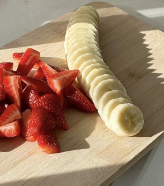Morangos e banana fatiada sobre tábua de madeira